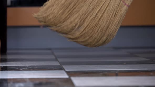 Young Girl Sweeps the Floor in the Kitchen with an Ordinary Broom