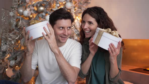 Cheerful Man and Woman Shake Present Boxes at New Year