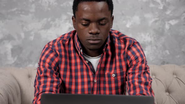 Concentrated African American Businessman Works Laptop Chatting with Employees