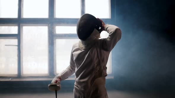 A Young Woman Fencer Putting on a Protective Helmet and Gets Into Position