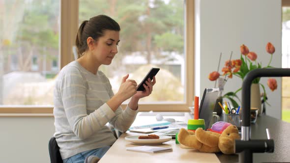 Young Woman with Smartphone Working at Home Office