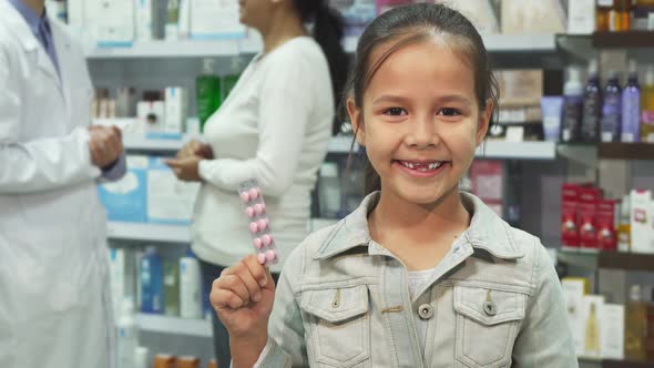 Little Girl Holding Medicine and Showing Thumbs Up