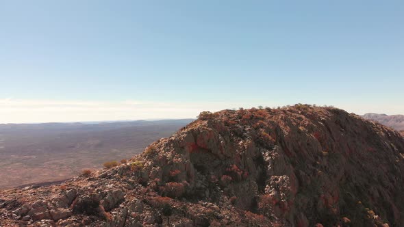 Aerial drone shot towards hikers climbing rugged mountain, Central Australia