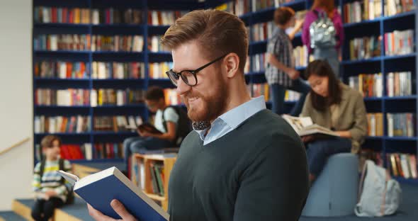 Portrait of Young Teacher Reading Book in School Library