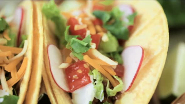 Ground beef tacos with romaine lettuce, diced tomatoes, radishes, and shredded cheddar cheese.