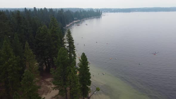 Counterclockwise drone shot revealing a beach from behind the trees at Payette Lake in McCall, Idaho