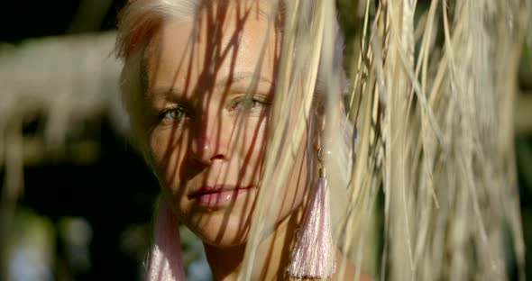 Close-up Portrait of a Green-eyed Blonde Girl with Short Hair, Her Ears Beautiful Earrings, Hanging