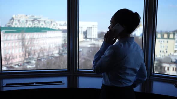 Businesswoman Answering Phone Call By Hotel Window