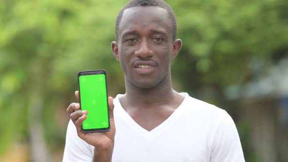 Young Happy African Man Smiling While Showing Phone in the Streets Outdoors