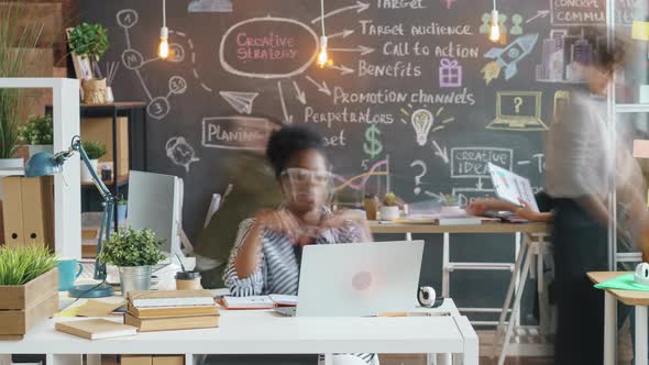 Zoomout Time Lapse of Business Men and Women Working with Laptops and Talking in Creative Office