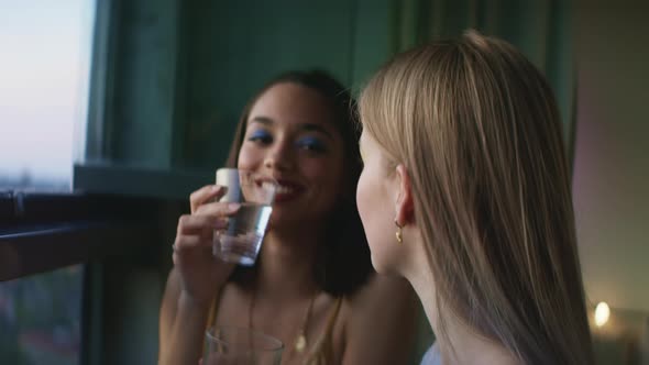 Two girls having drinks and talking on the balcony