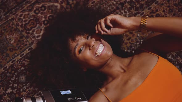 Woman With Afro Hair Smiling On Floor With Vintage 8Mm Camera