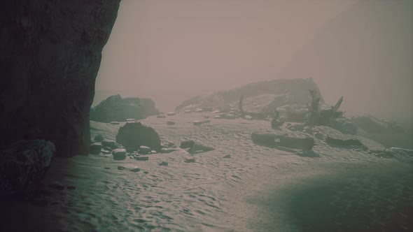 Rocky Cliff with Sand Beach in Deep Fog