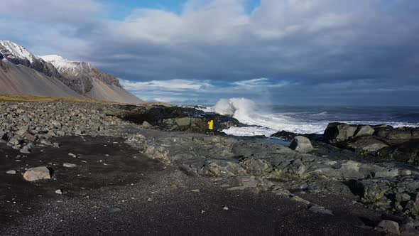 Drone Of People On Rocky Shore Of Black Sand Beach With Crashing Waves