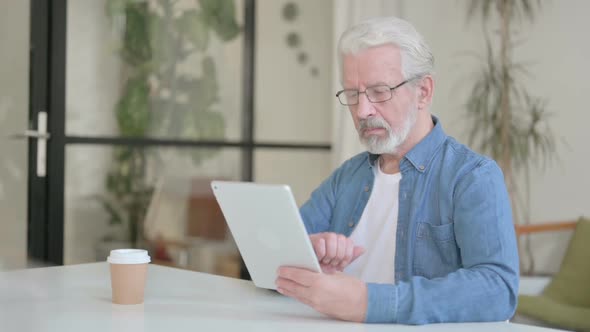 Attractive Senior Old Man Using Tablet in Office