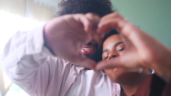 Young Arabian Man and African American Woman Making Joint Gesture Heart