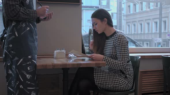 Pretty Girl Makes an Order. The Waiter Listens To Her Attentively and Write Down Everything