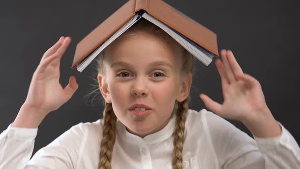 Pretty Schoolgirl With Book on Head Laughing and Fooling Around, Childish Mood