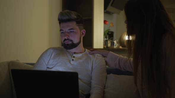 Man working on his laptop and ignoring his wife