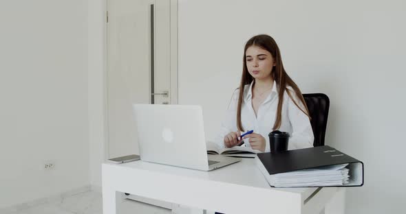 Cheerful Girl Having Online Communication on Laptop at Workplace in Light Office