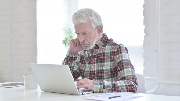 Casual Old Man Thinking and Working on Laptop 