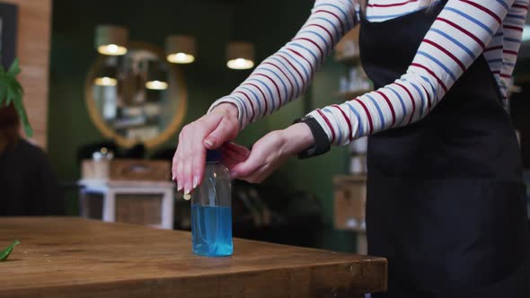 Mid section of female hairdresser sanitizing her hands at hair salon