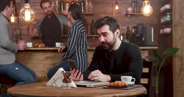 Young Handsome Man Engaged in a Video Call While Serving His Coffee in a Cafe