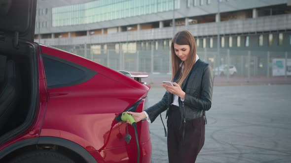 Beautiful Woman Using Smartphone While Charging Car