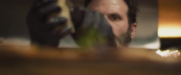 Close up of Italian chef in black gloves slicing parmesan cheese, slow motion, low angle.