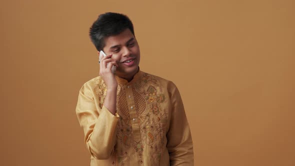 Positive Indian man in national cloth talking by phone