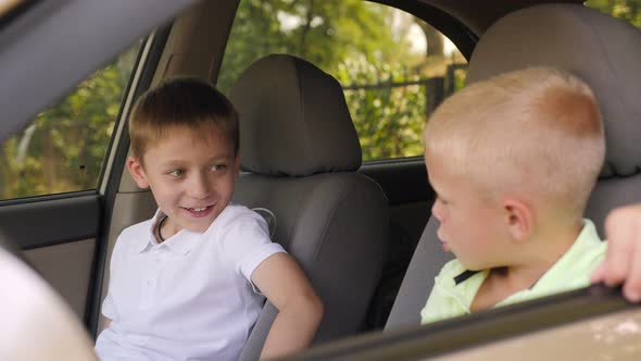 Closeup of the Little Brothers Sitting Behind the Wheel of a Car and Playing