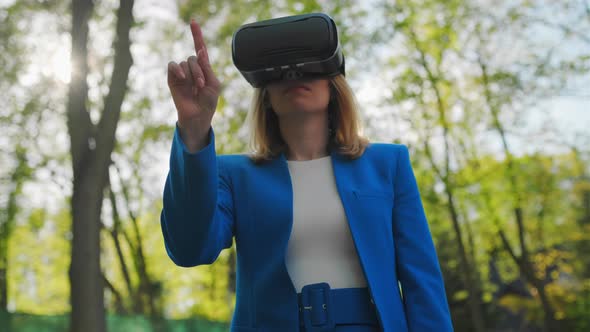 Business Woman Controls the Virtual Interface By Pressing Buttons with Her Finger in VR Goggles