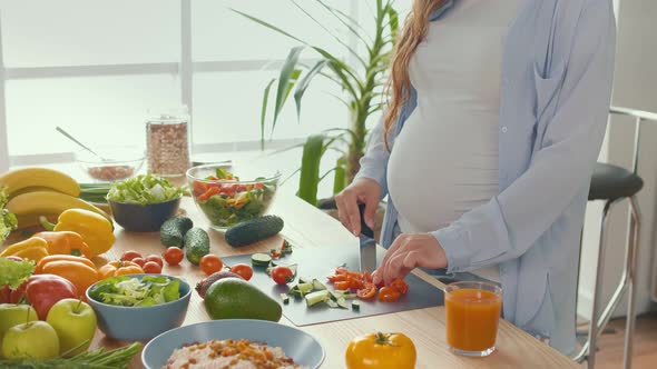 Pregnant Woman in the Kitchen Cuts Tomatoes Prepares Dinner