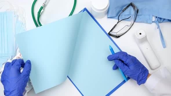 doctor in white coat and blue latex gloves flips through blue blank pages 