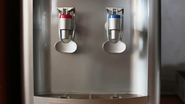 Human Hand Pouring Cold Water in Glass From Water Dispenser