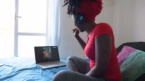 Young woman sitting on bed during video call via laptop