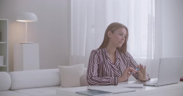 Young Pretty Student Woman Is Learning Online at Home, Sitting at Table, Watching Webinar at Laptop