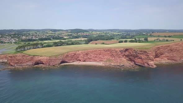 4K aerial,ing toward red cliffs along the Jurassic Coast world heritage site