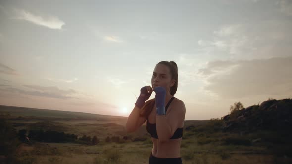 Woman Looks Intently Into the Distance Practicing Blows in Fresh Air Front View