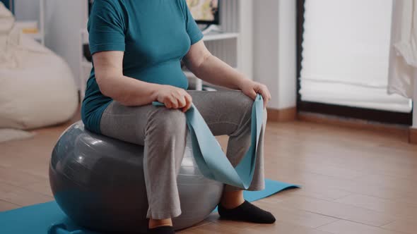 Retired Adult Training with Resistance Band on Fitness Toning Ball