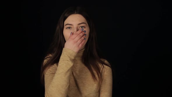 A Young Caucasian Girl Coughing and Look at the Camera. Isolated Black Background. Coronavirus