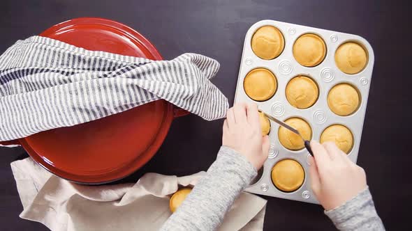 Step by step. Top view. Removing freshly baked cornbread muffins from metal muffin pan.