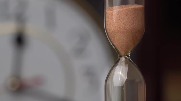 Hourglass Closeup is Pouring Against the Background Ordinary Mechanical Watch