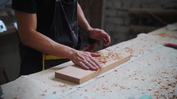Carpentry Works in Workshop Man Worker Brings the Wooden Board to the Table and Shakes Off the