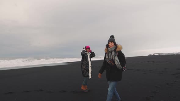 Friends Traveler Walking on Volcanic Black Sand Beach in Iceland