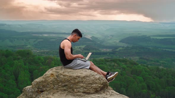 Male Freelancer Typing on Notebook Keyboard Outdoors Sunset and Stunning Scenery