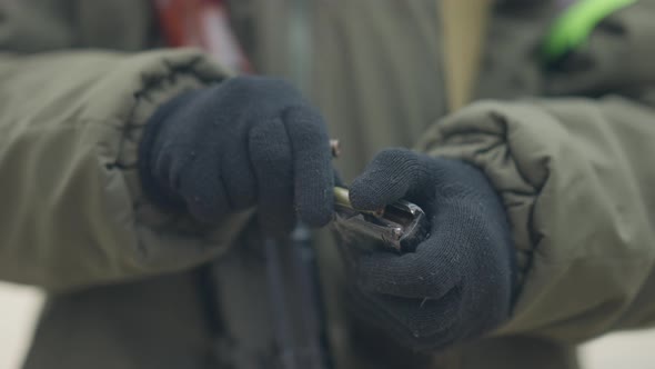 Closeup of Female Hands in Gloves Loading Bullets in Magazine