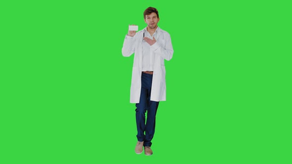 Walking Male Doctor Showing Empty White Box of Pills on a Green Screen, Chroma Key.