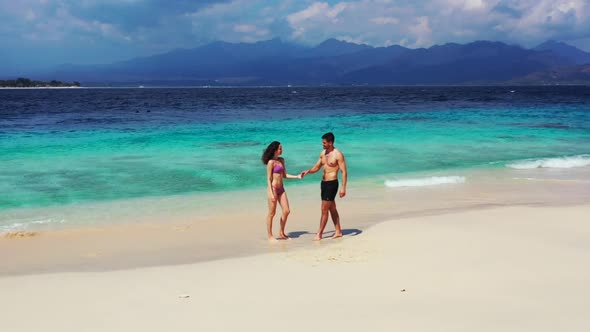Teenage lovers tan on idyllic shore beach vacation by aqua blue ocean with white sand background of 