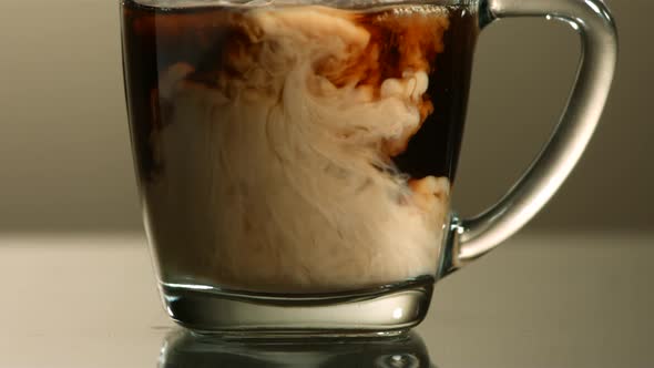 Milk poured into coffee in ultra slow motion 